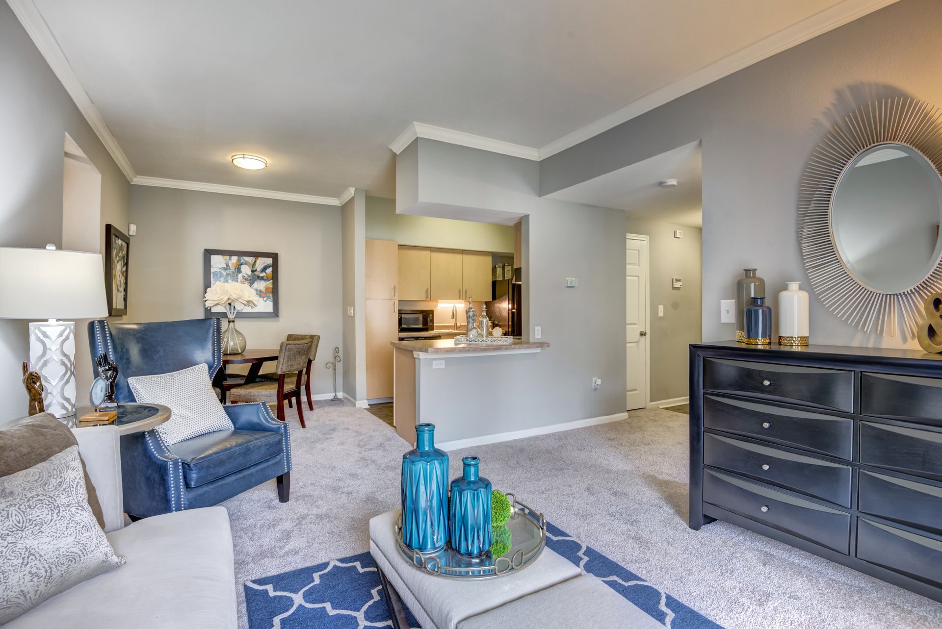 A living room with a couch , chair , coffee table , dresser and mirror.