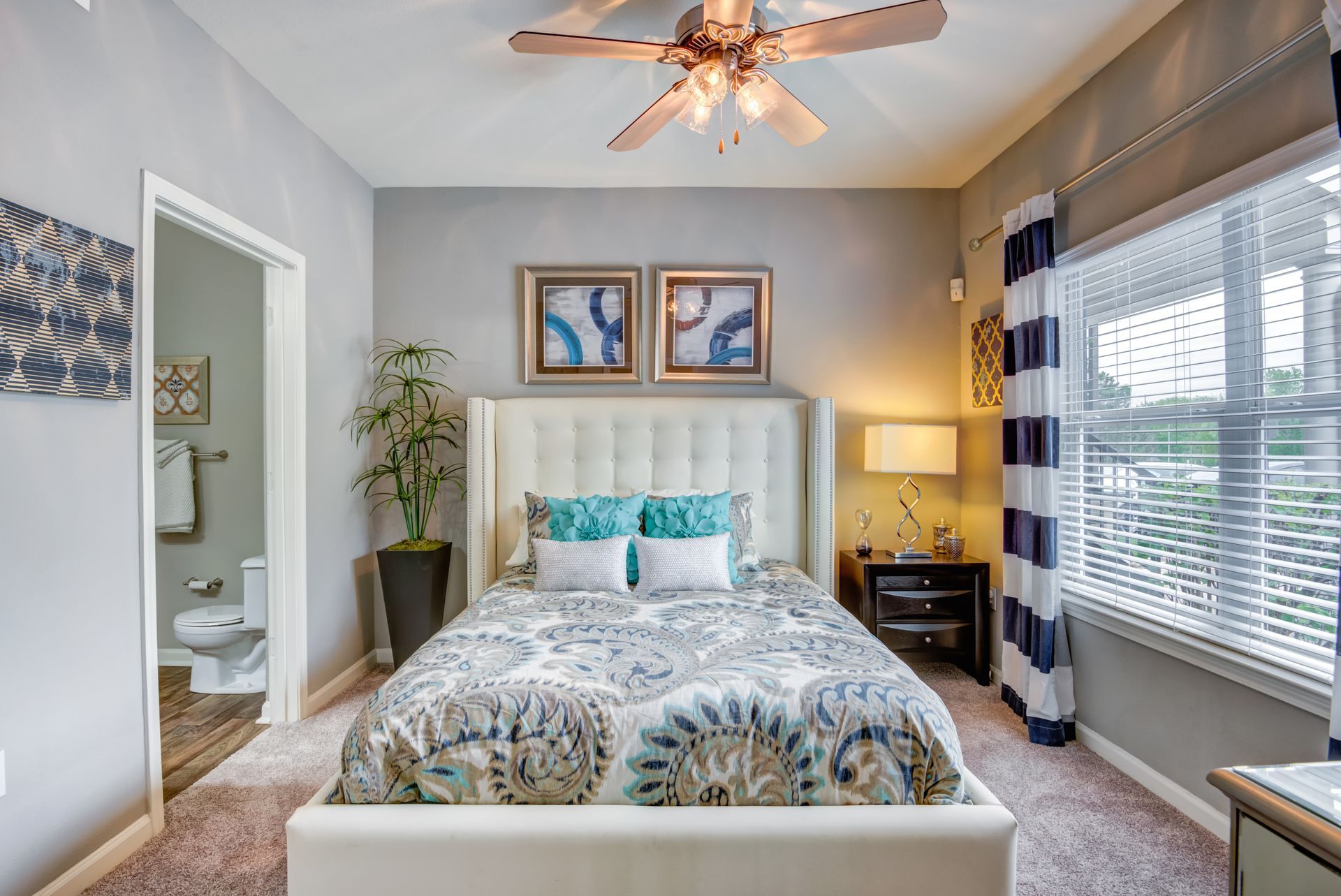 A bedroom with a ceiling fan , a bed , a window and a toilet.
