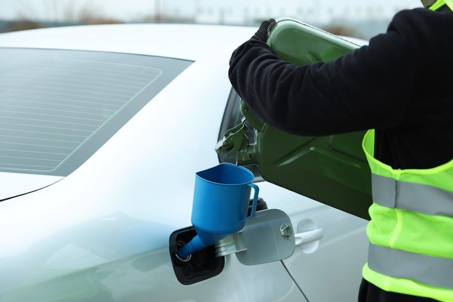 A man is pouring gas into a white car.