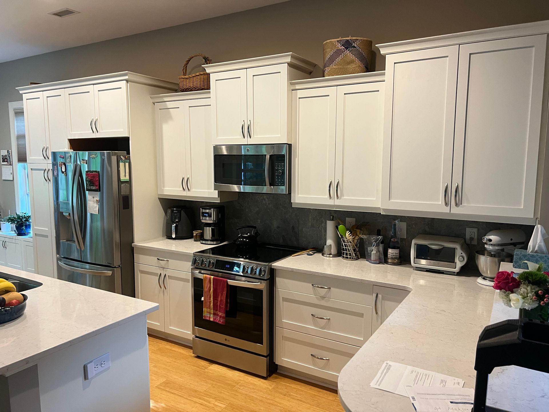 A kitchen with a bar and green chairs and a vase of flowers on the counter.