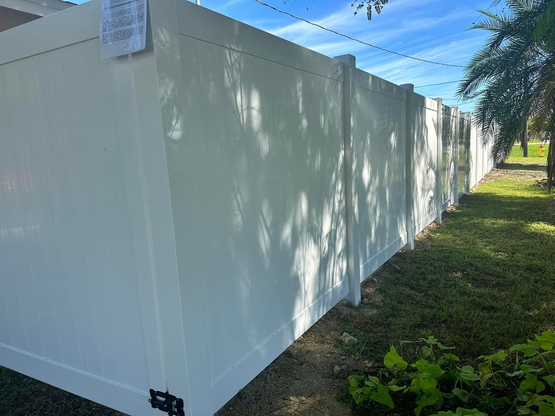 White vinyl privacy fence in a yard on a sunny day.