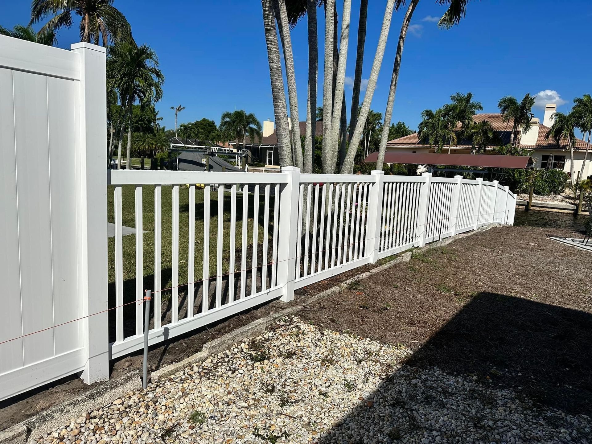White picket fence along a yard, in a sunny outdoor setting.