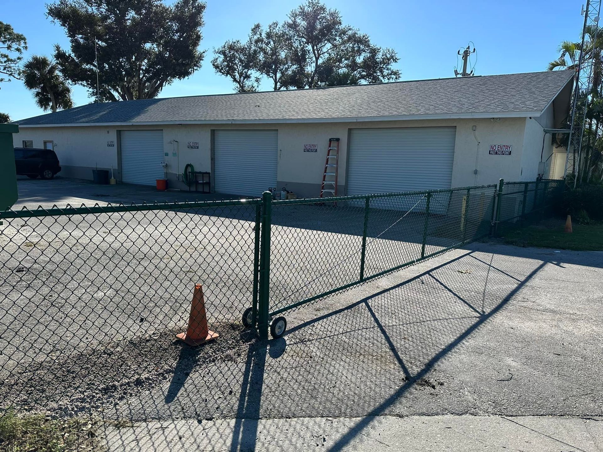 A long, one-story building with three garage doors and a chain-link fence in front.