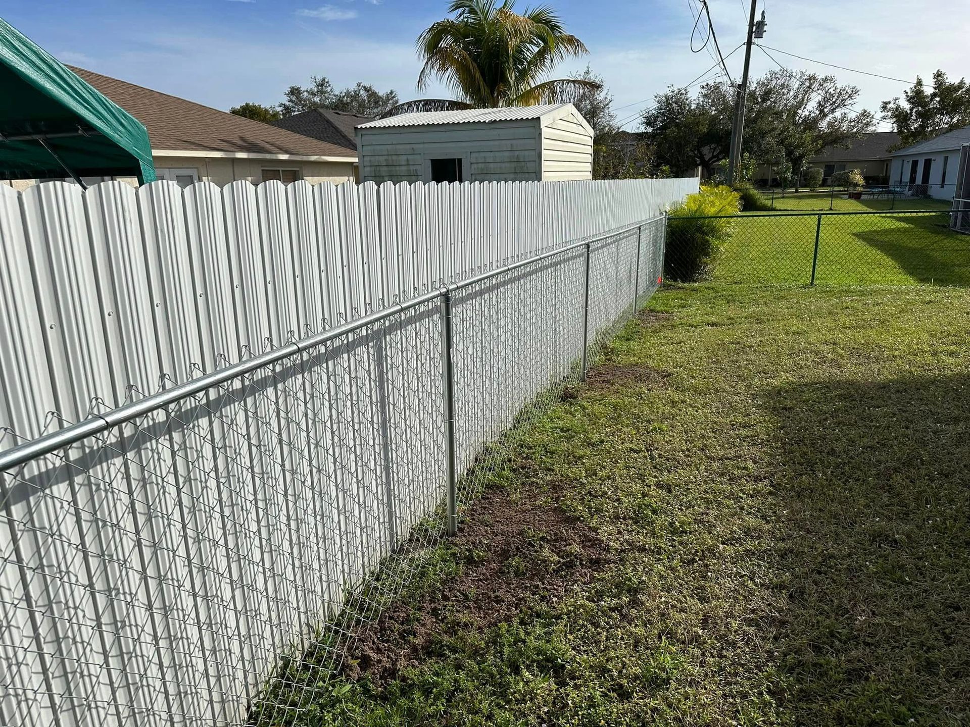 White decorative metal fence bordering a grassy yard on a sunny day.