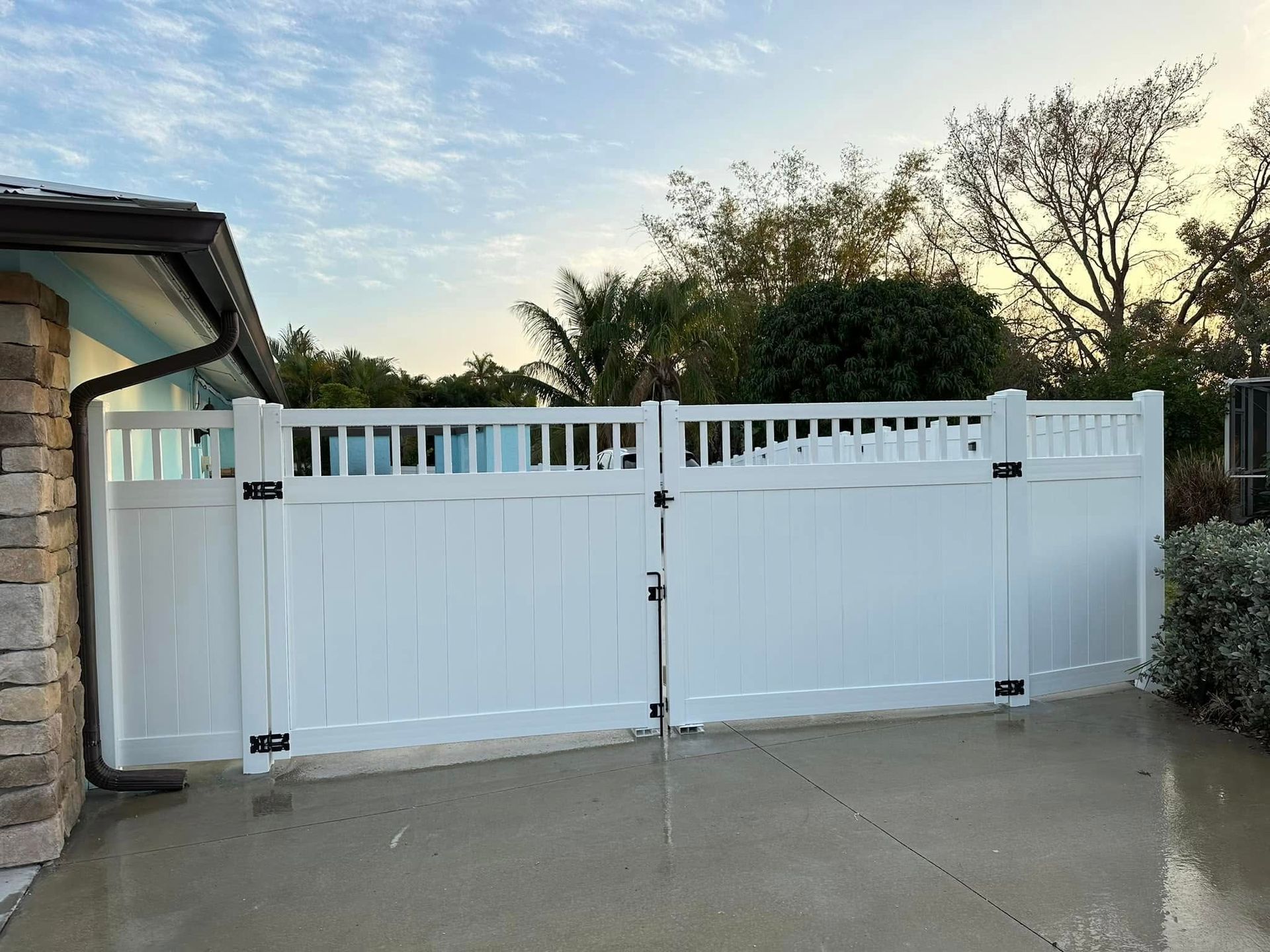 White vinyl double gate in a backyard setting.