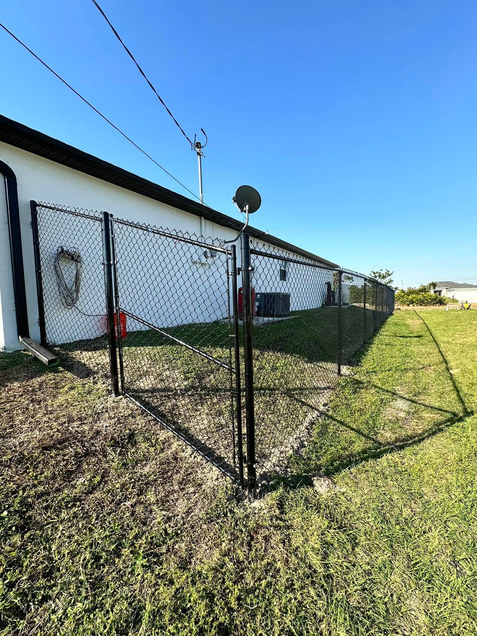 Black fence along a white building, on a grassy lawn under a blue sky.