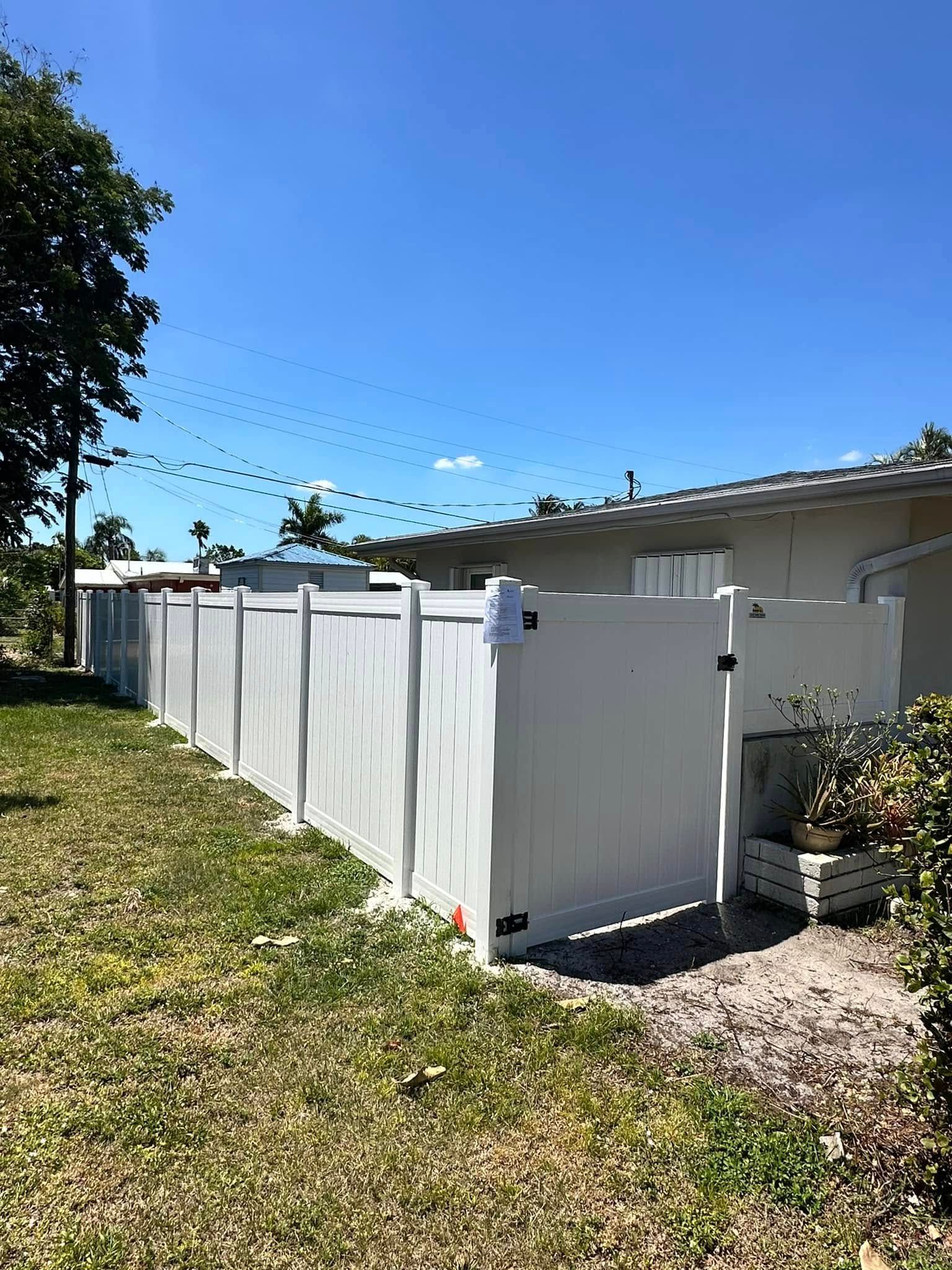 White vinyl fence surrounding a yard on a sunny day.