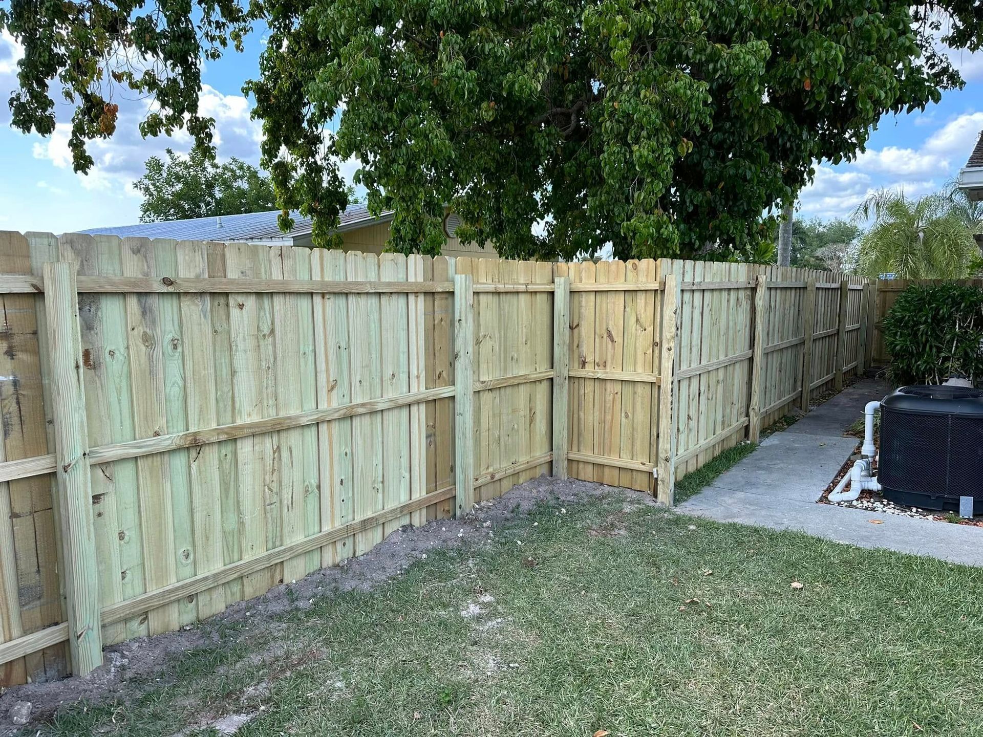 Wooden fence in a backyard, with a gate and lush green grass.