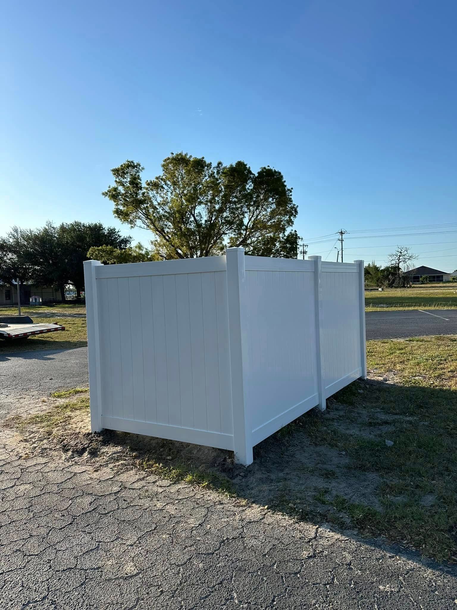 White vinyl fence in a grassy area with a clear blue sky.