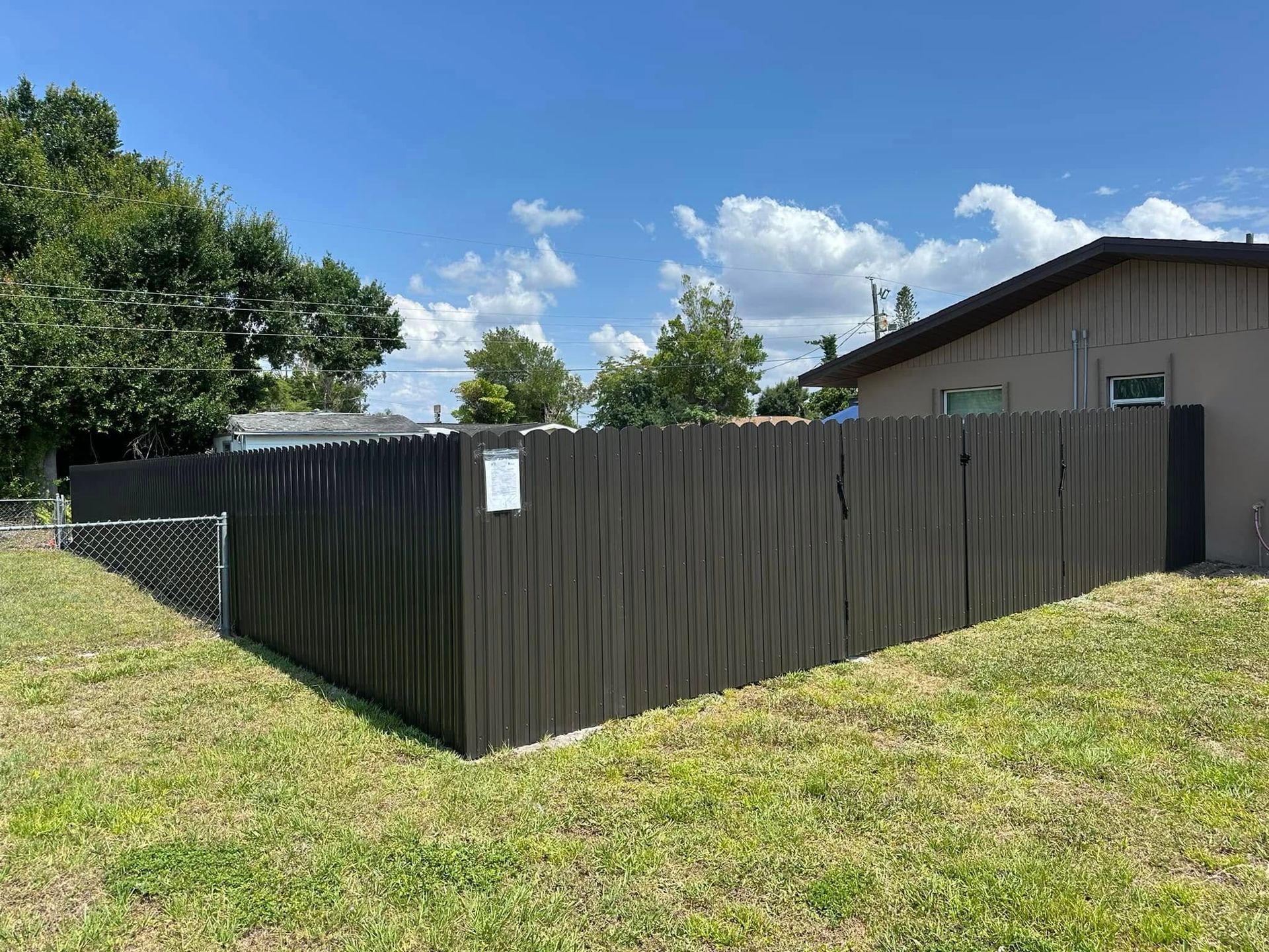 Black wooden fence in a backyard on a sunny day.