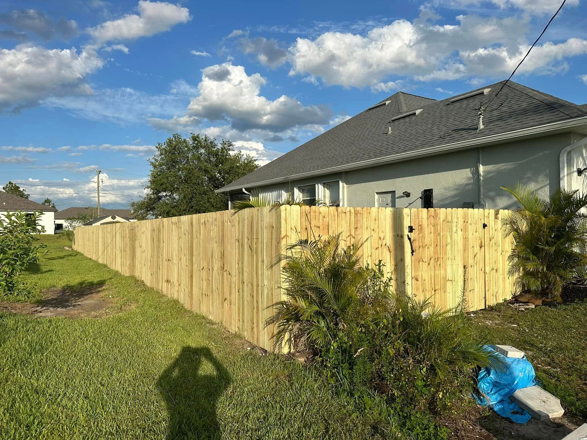 Wooden fence around a house, under a blue sky.