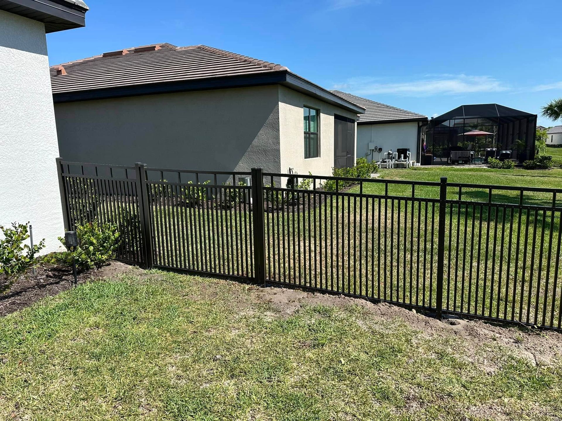 Black metal fence in a grassy yard, between houses.