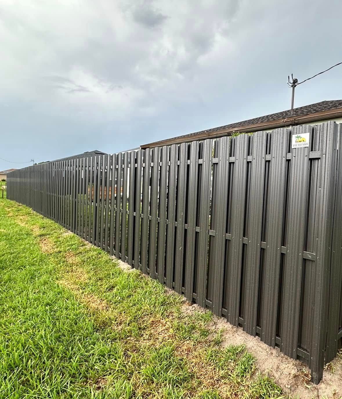 Dark grey vertical slat fence bordering a grassy yard and adjacent to a tiled roof.