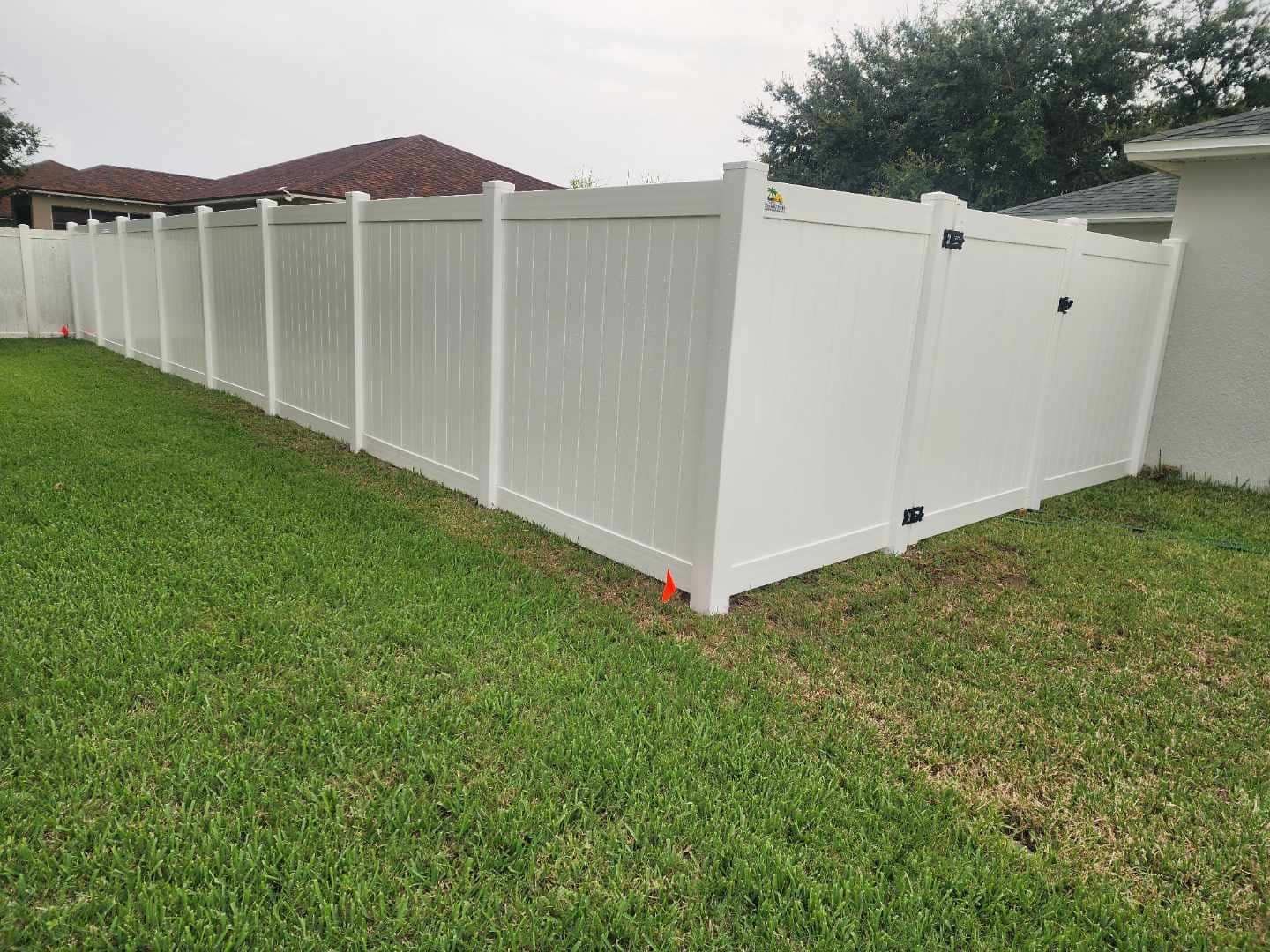 White vinyl fence in a grassy yard, separating properties.