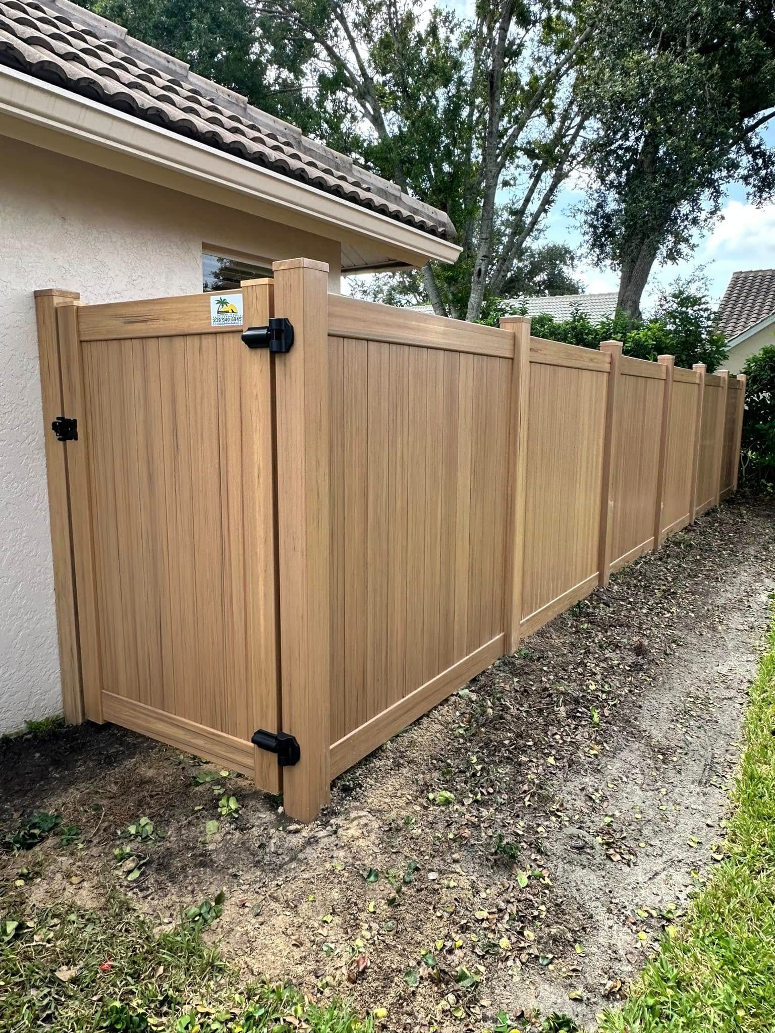 Tan wooden fence with gate near a house, in a yard.