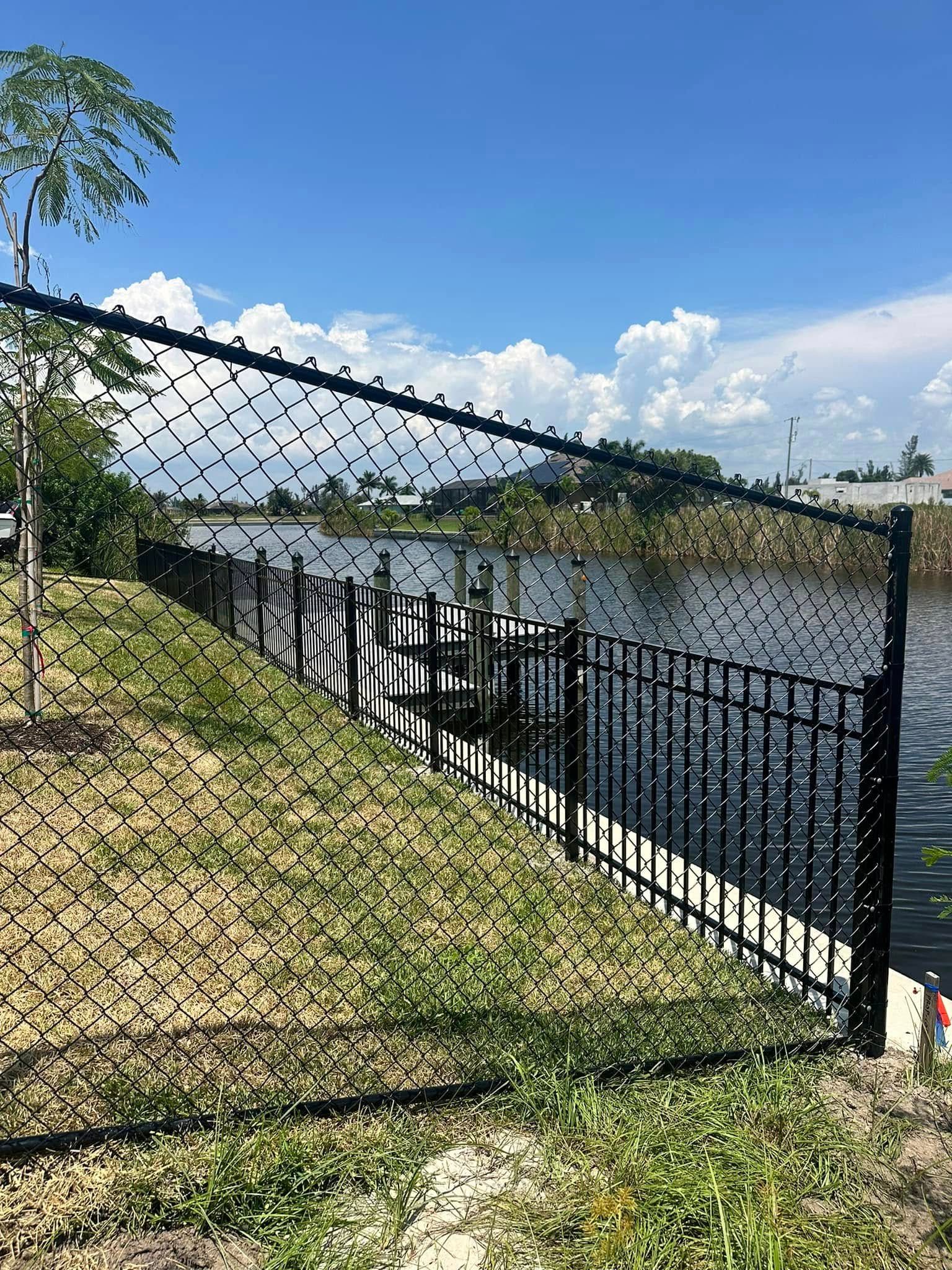 Black metal fence along a canal, under a blue sky with clouds.