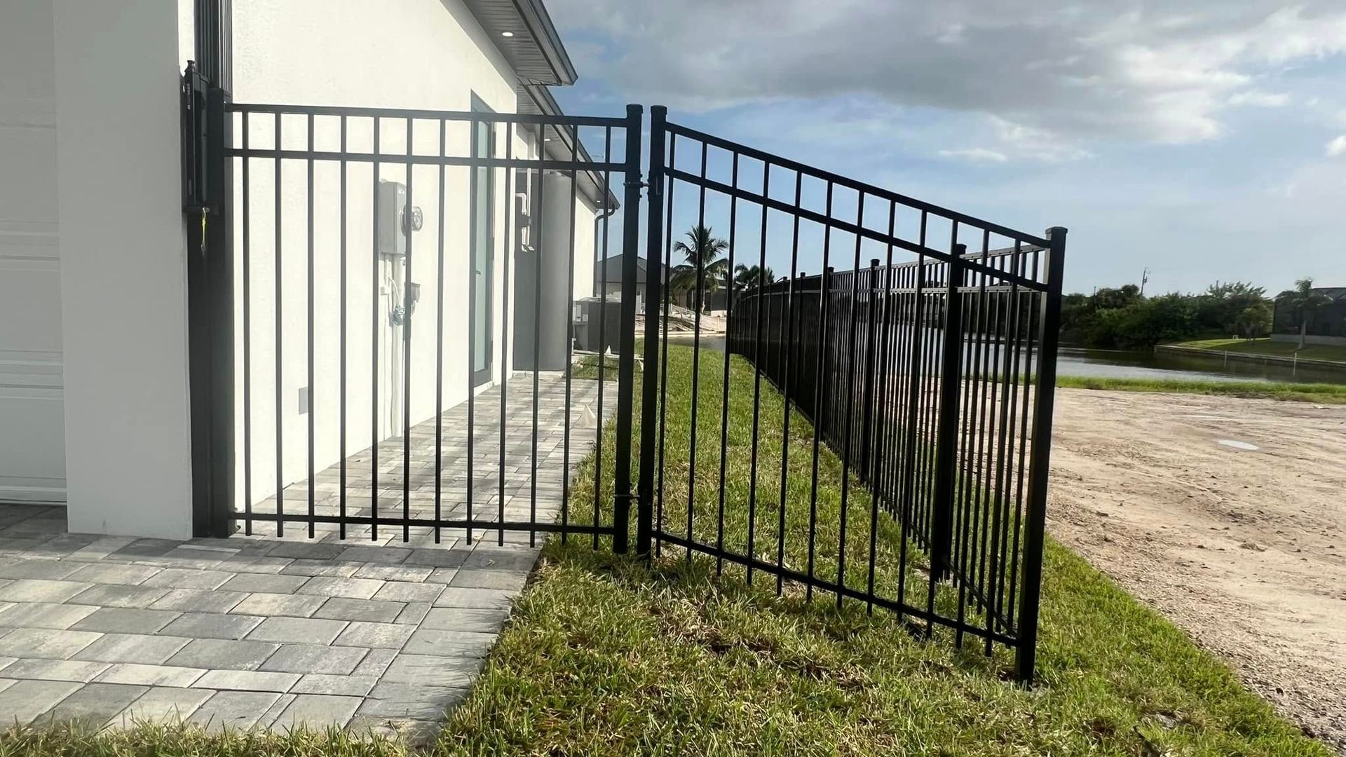 Black metal fence along a home's exterior, with a gate.