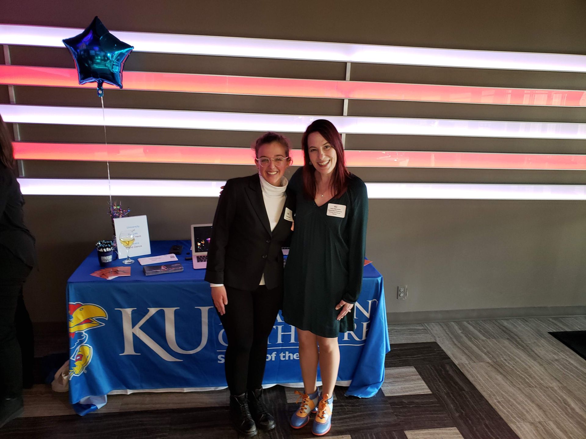 Two women pose by a table with a 