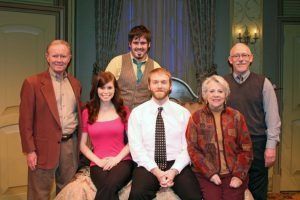 Group of six people posing on a stage, possibly for a play.