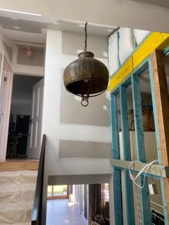 A large rustic metal pendant light hangs in a hallway — Channel Electrical In Swansea Heads, NSW