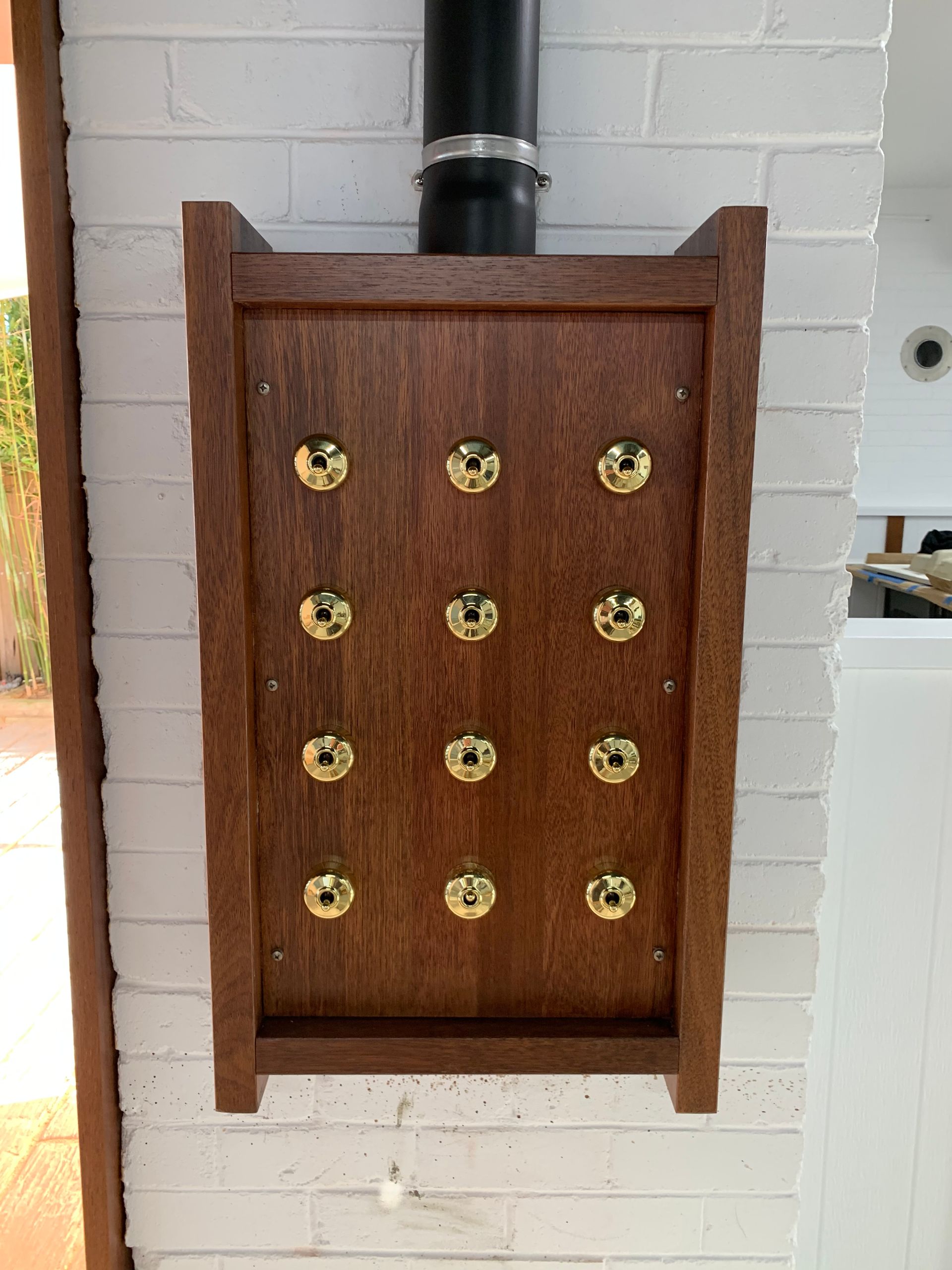 A wall-mounted, rectangular wooden board with polished brass knobs — Channel Electrical In Swansea Heads, NSW