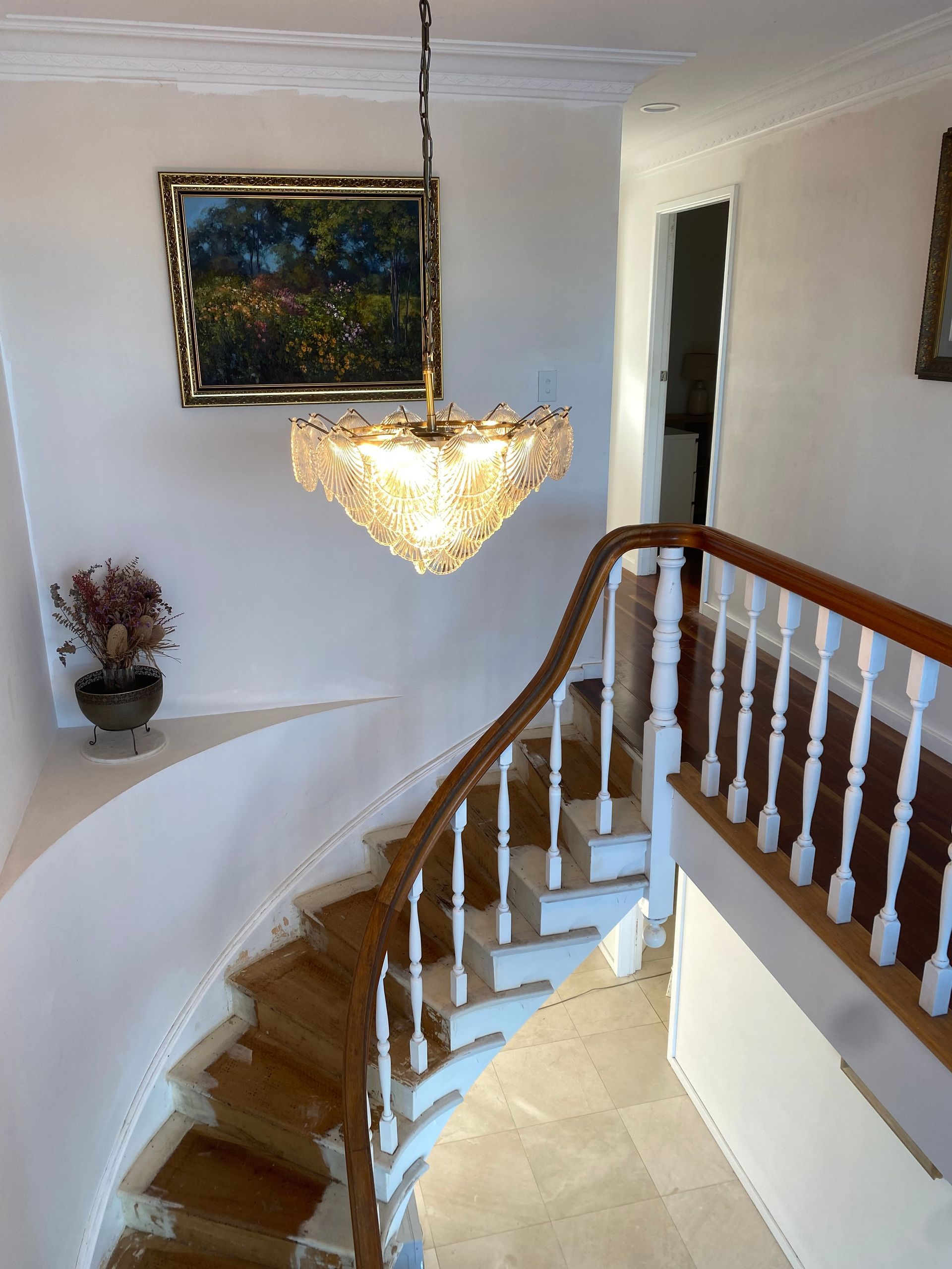 A curved staircase with a wooden handrail and white spindles — Channel Electrical In Swansea Heads, NSW