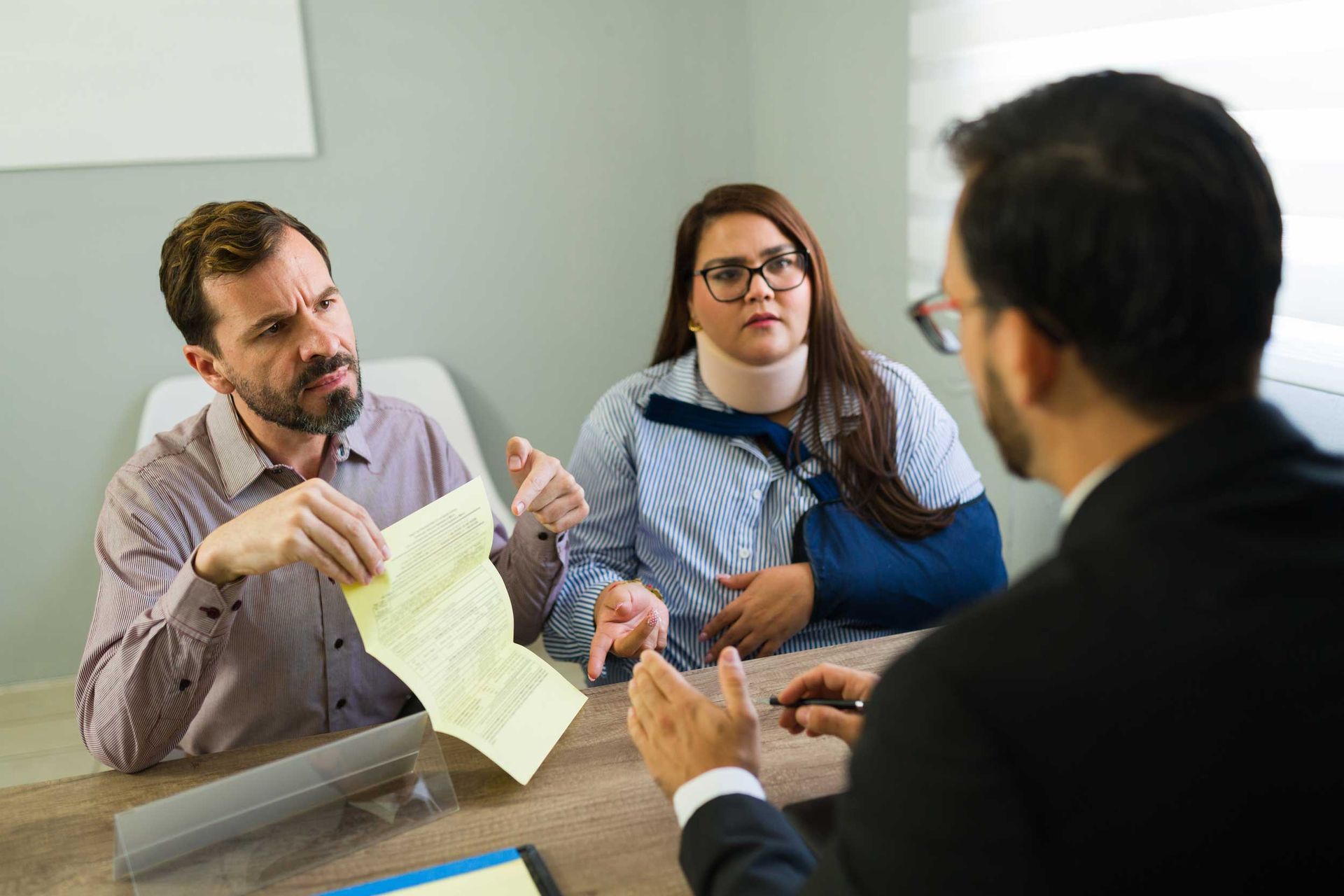 Injured couple discussing insurance claim with lawyer.