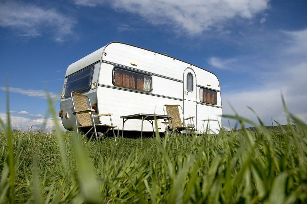 A White Trailer Is Parked In A Grassy Field — Tim Warren Auto Airconditioning & Electrical In Bowen, QLD