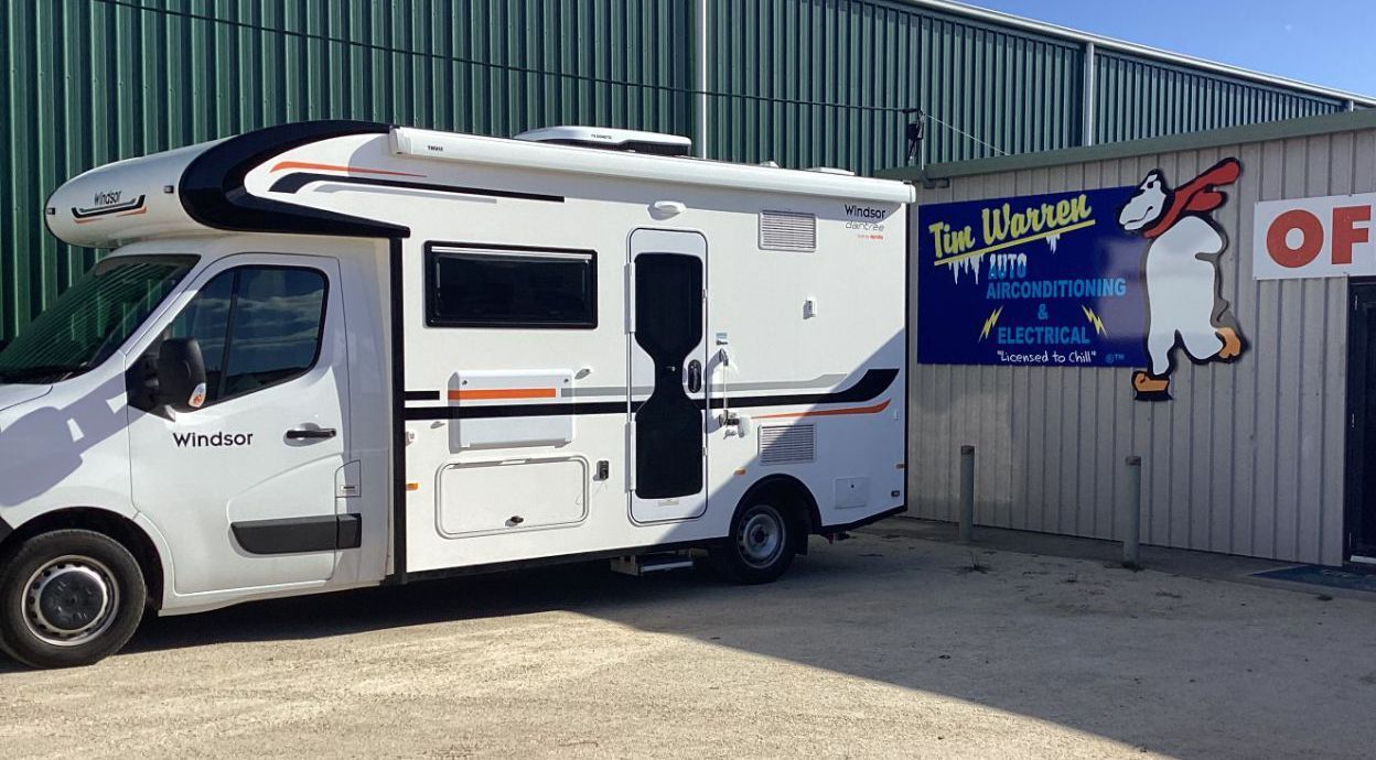 A Caravan Is Parked On The Beach Next To The Ocean — Tim Warren Auto Airconditioning & Electrical In Bowen, QLD