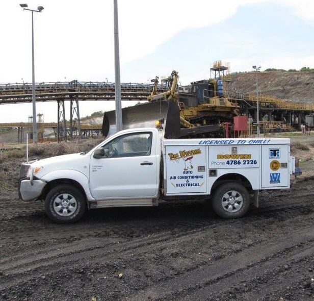 A Man Is Fixing A Car Battery With A Wrench — Tim Warren Auto Airconditioning & Electrical In Bowen, QLD