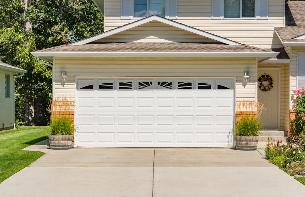 A white garage door is sitting in front of a house.