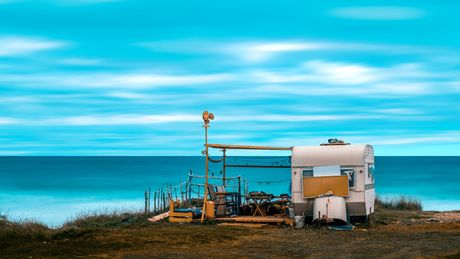 Trailer on a grassy cliff overlooking the ocean, with blue sky and sea.