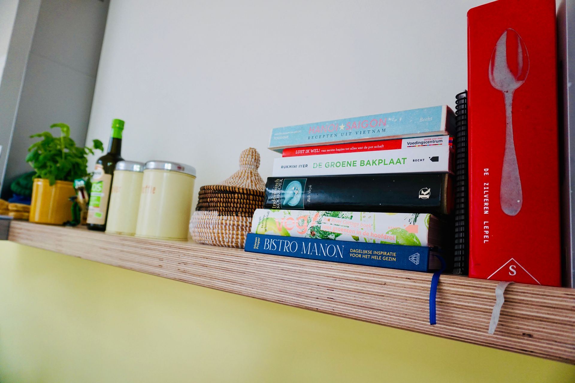 Een plank met een stapel boeken en een rood boek met een lepel erop.