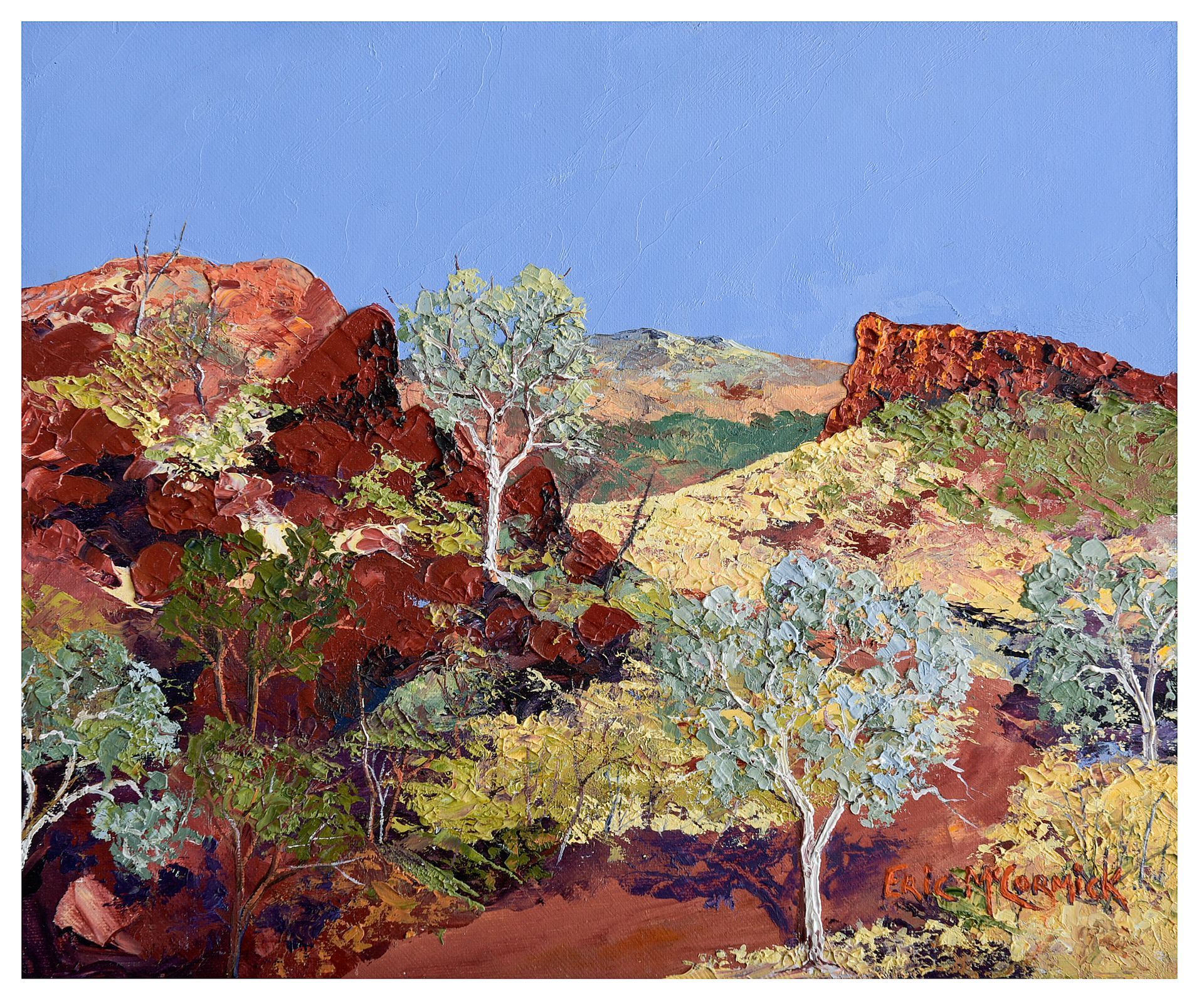 Red rocks and sparse trees under a blue sky in an Australian desert landscape.By The artist Eric McCormick
