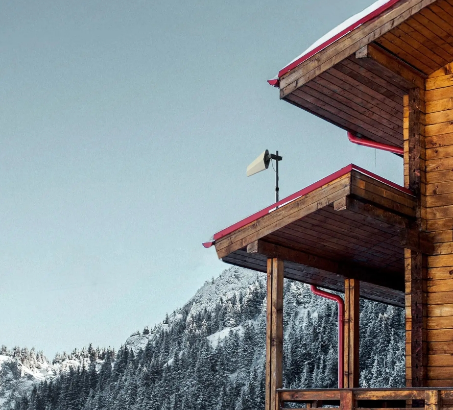 Snowy mountain chalet with wooden balconies and red trim under a clear sky