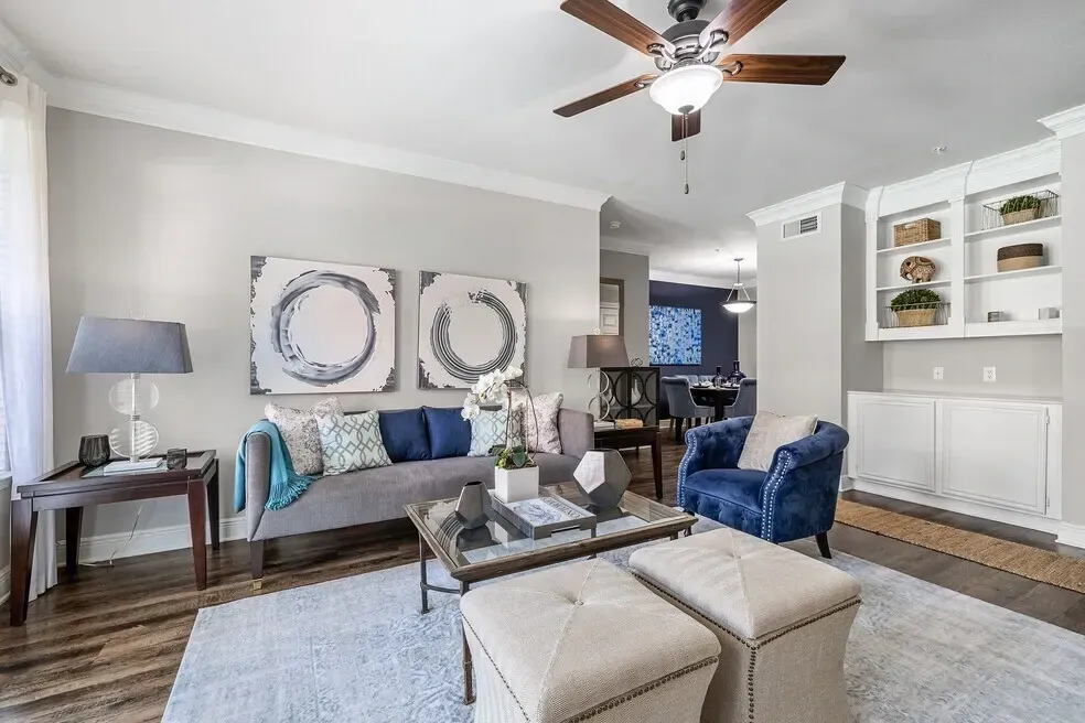Stylish living room with gray sofa, blue accent chair, coffee table, and ceiling fan.