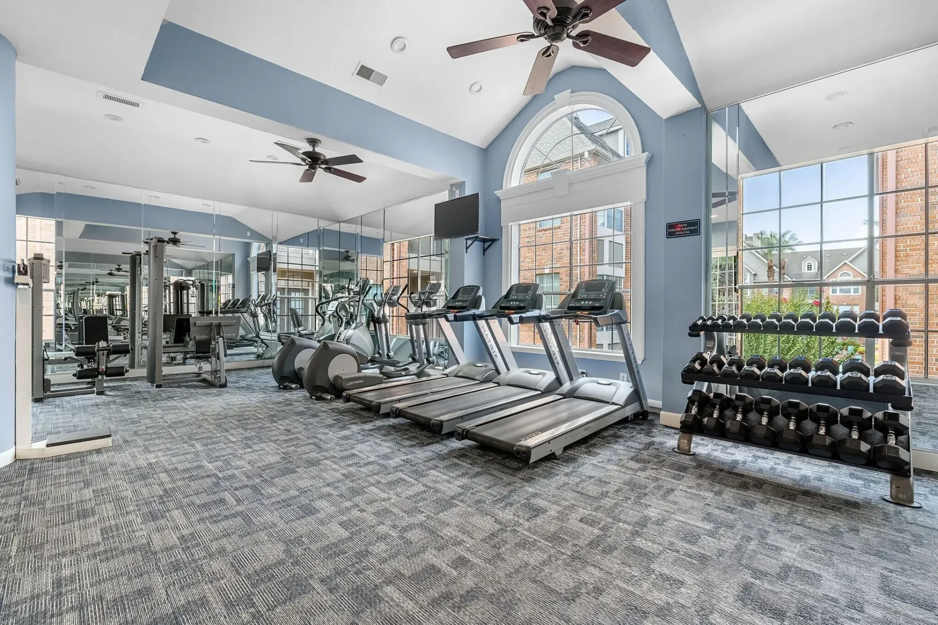 Fitness center with treadmills, ellipticals, weight machines, and a dumbbell rack.