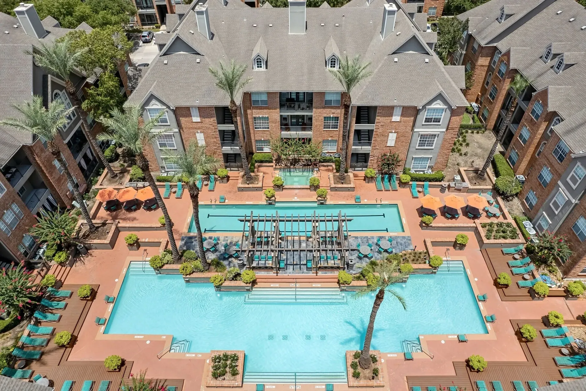 Aerial view of a resort-style swimming pool and lounge area surrounded by apartment buildings.