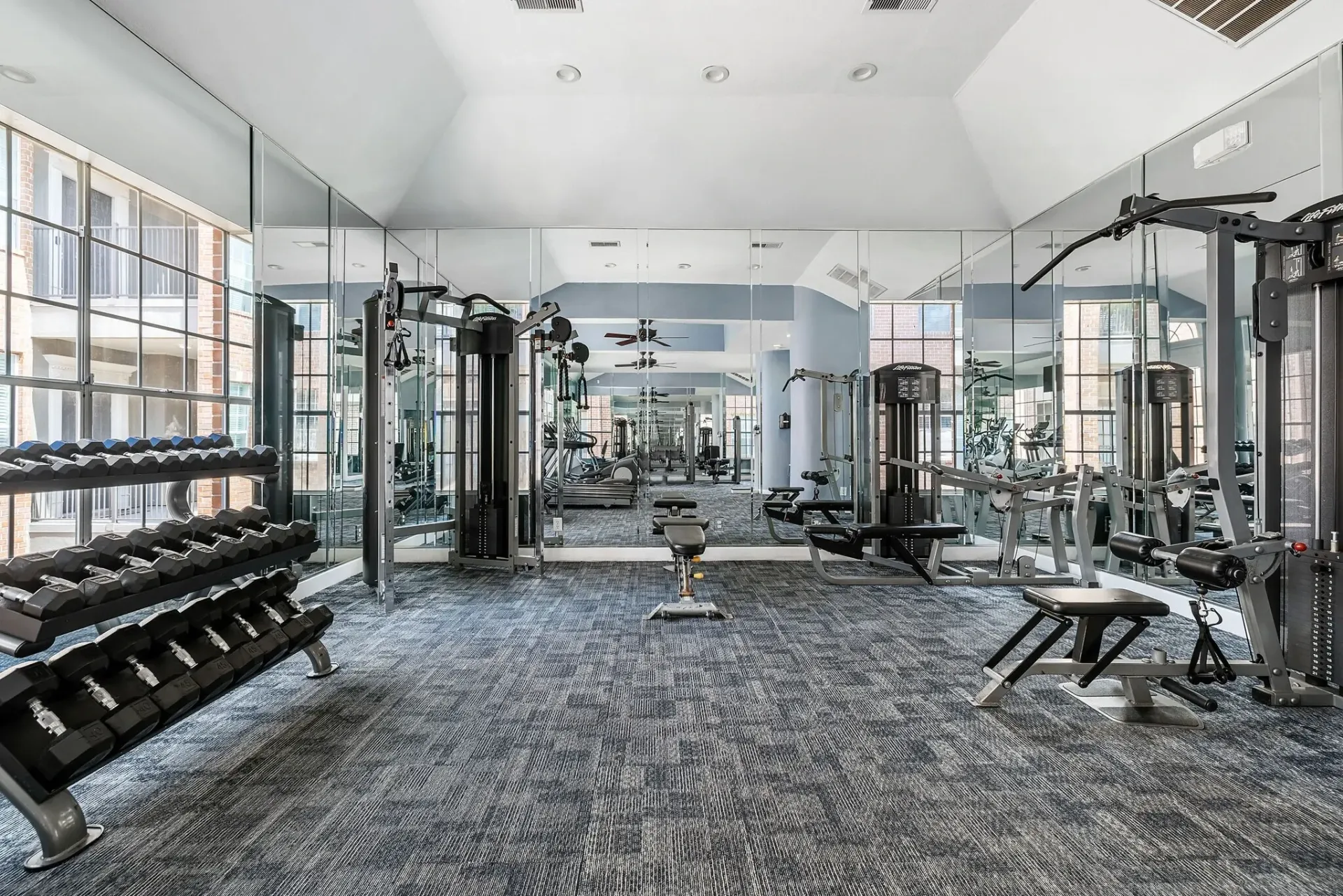 Well-equipped fitness center with dumbbells, weight machines, and treadmills.