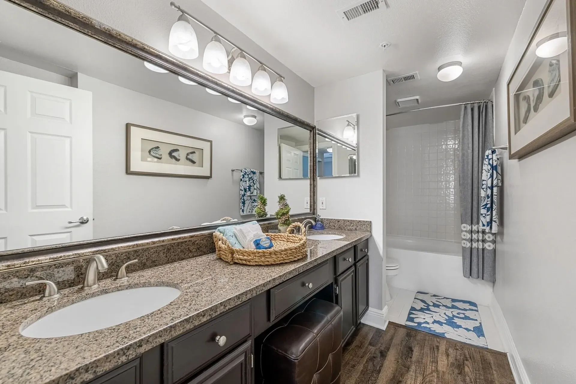 Bathroom vanity with granite countertops, dual sinks, and a large mirror.
