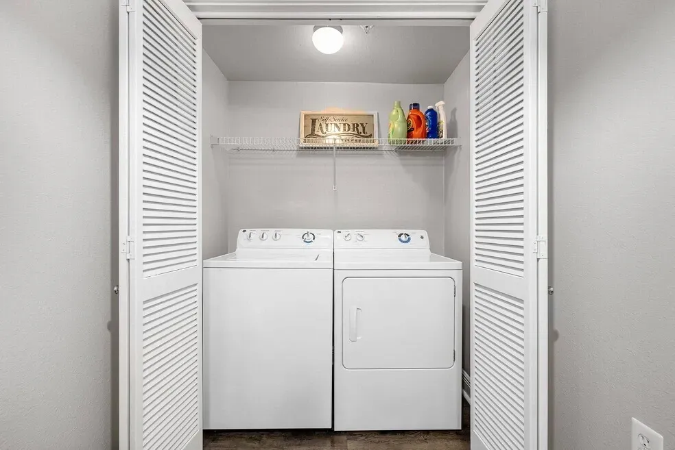 Stackable white washing machine and dryer in a closet.