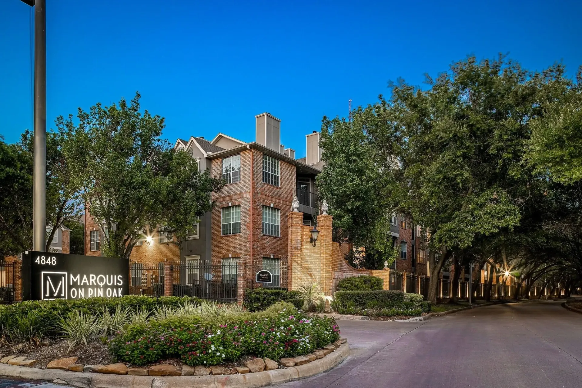 Marquis on Pin Oak apartment building exterior at dusk with exterior lighting and landscaping.