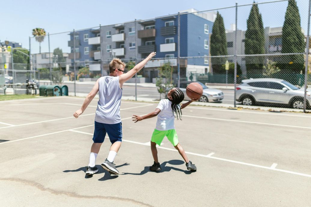 A man and a girl are playing basketball on a court.