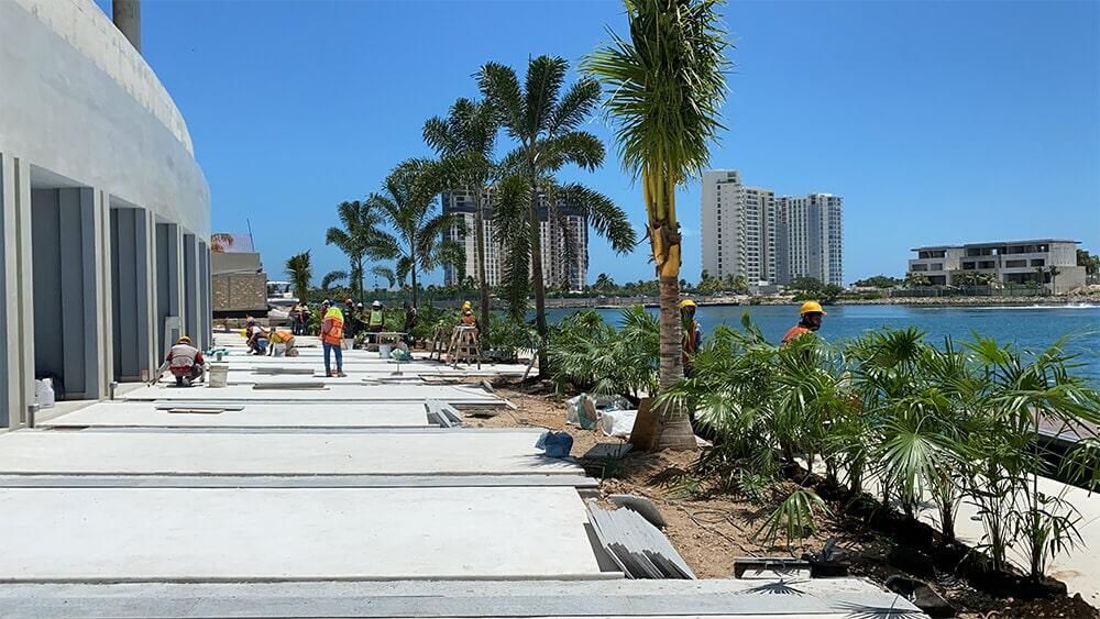Un grupo de trabajadores de la construcción está trabajando en un edificio al lado de una masa de agua.