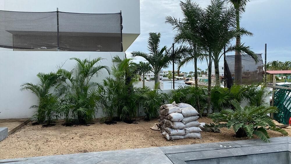 Una pila de sacos de arena está en un jardín al lado de un edificio.