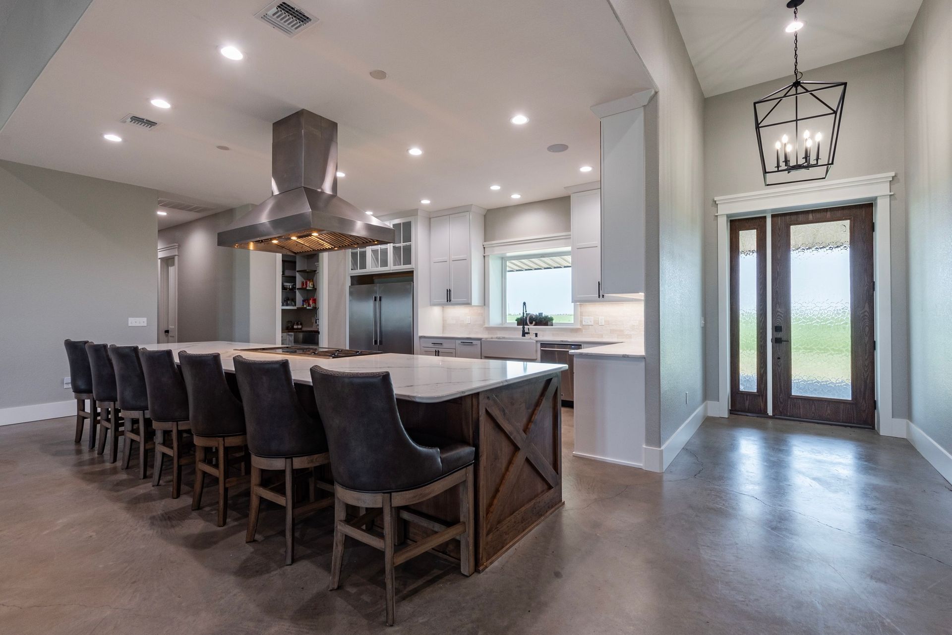 Spacious modern kitchen with large island, seating, stainless steel appliances, and wood and grey accents.