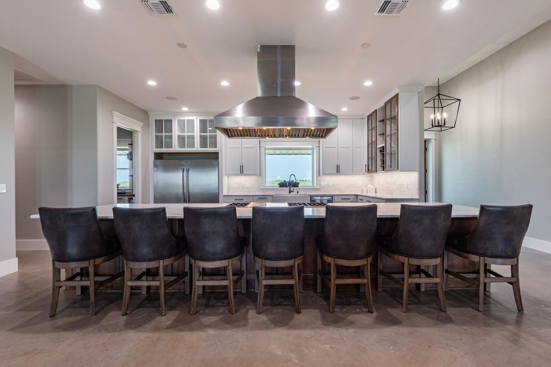 Modern kitchen with a large island and eight dark leather bar stools.