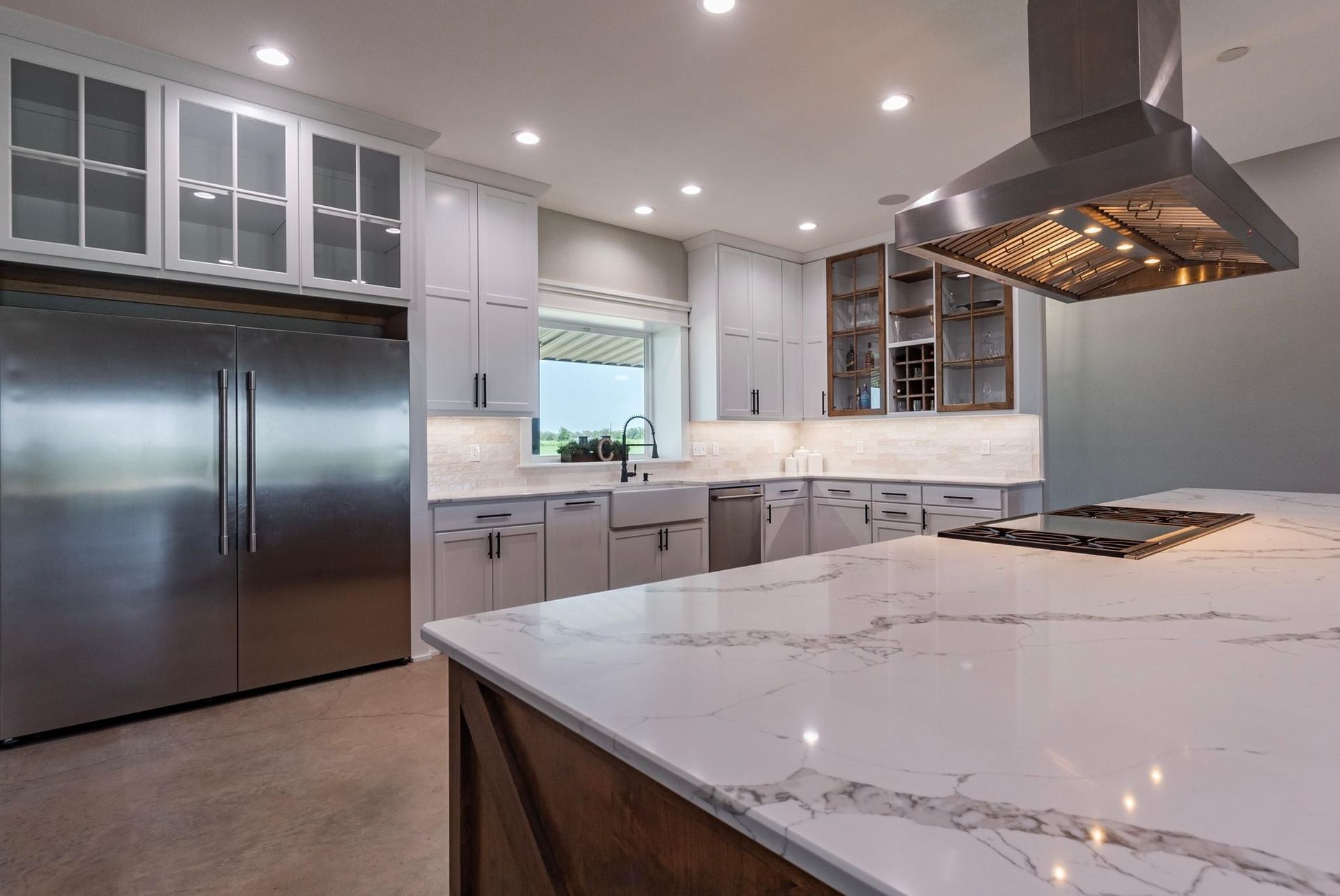Modern kitchen with stainless steel appliances, white cabinets, and large island with marble countertop.