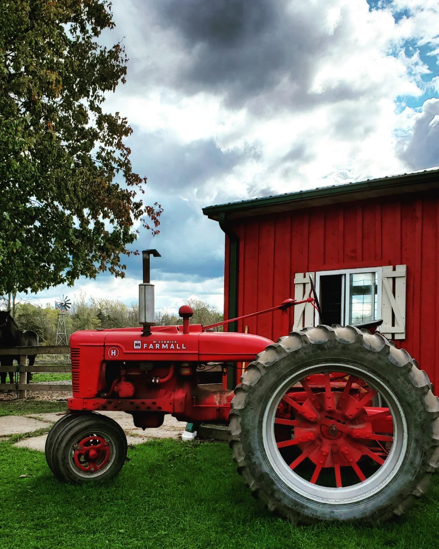 A red farm tractor in front of a red barn