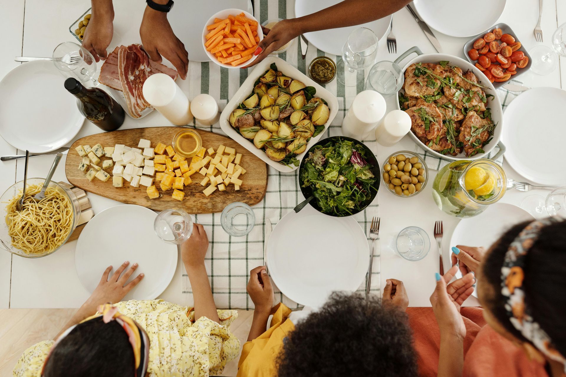 A dining table with food surrounded by a family of people